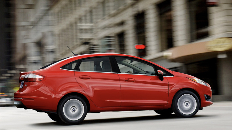 Red Ford Fiesta driving through a city