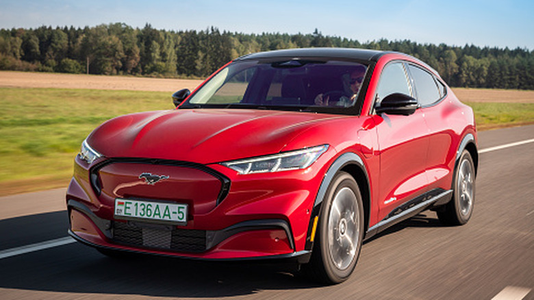 Minsk, Belarus - September 10, 2021: All-electric bright red Ford Mustang Mach-E drives on a highway during a sunny day.