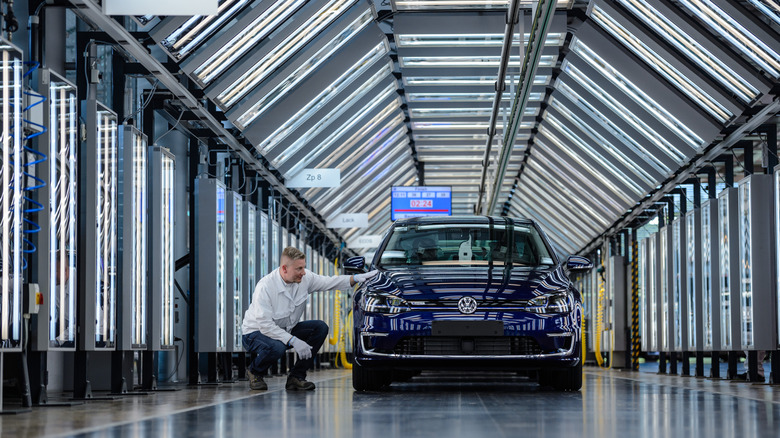 DRESDEN, GERMANY - MAY 08: An employee inspects a Volkswagen e-Golf electric automobile in the light tunnel inside the Volkswagen AG (VW) factory on May 8, 2018 in Dresden, Germany. From the beginning of May, the car manufacturer has increased its output and is now producing a total of 72 Volkswagen e-Golf electric cars each day at the factory.