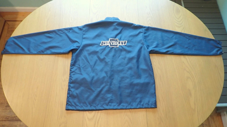 The back of a vintage blue Chevrolet jacket laid out on a wood table