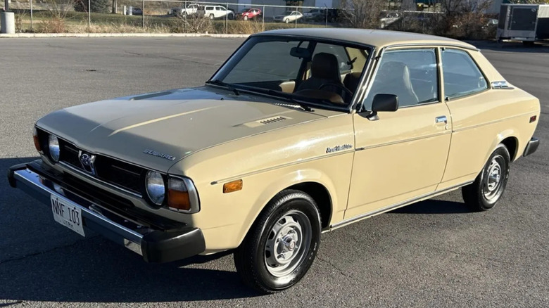 What is likely a much, much nicer Subaru DL, 1 yellow/creme 1979 2-door photographed in a parking lot.
