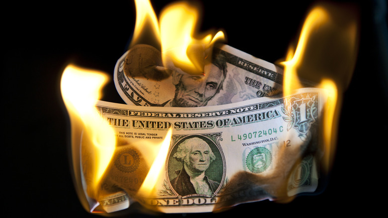 Burning US five and one dollar bills, London, 8th August 2011.