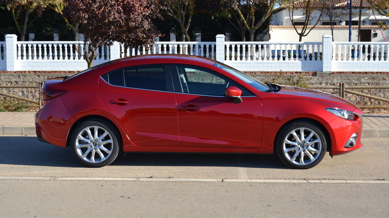A red 2016 Mazda 3 sedan parked on a residential street