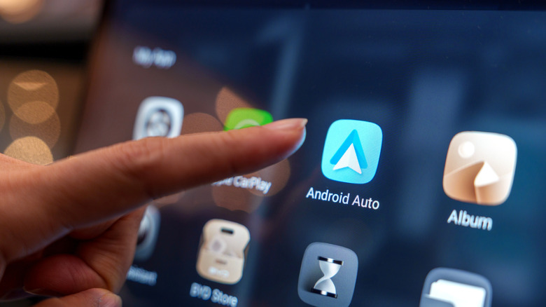 Close-up of a user interacting with the Android Auto pairing interface on the digital display inside a BYD electric car at an auto show in Penang.