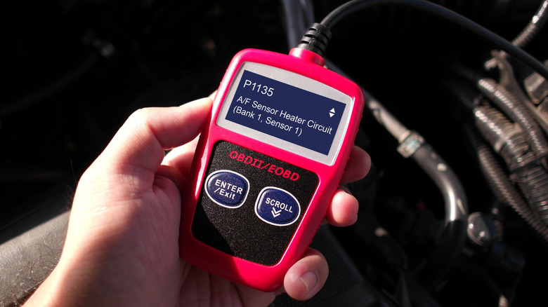OBD or OBD-II scanner in use by technician , Automotive diagnostic tool in use for scanning fault code of car engine system , Car repair concept