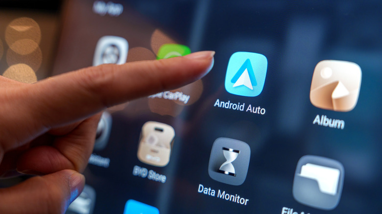 Close-up of a user interacting with the Android Auto pairing interface on the digital display inside a BYD electric car at an auto show in Penang.