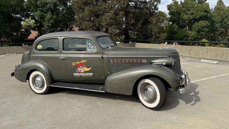 A side view of a dark gray '37 Buick Series 40 Special Touring Sedan parked on a rooftop parking structure