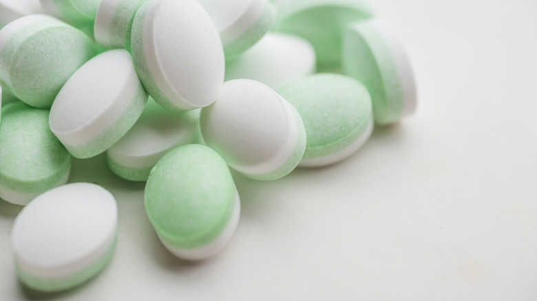 What appears to be some larger-than life mints with a green side and a white side, but is really just a macro-lens close up of mints on a white surface.