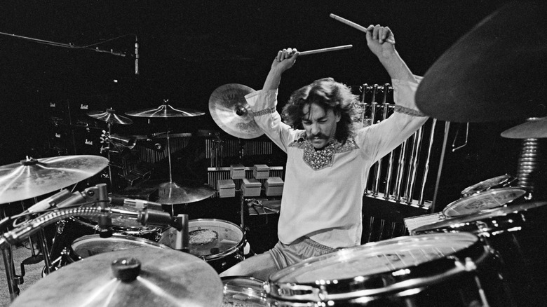 Neal peart banging away at the drums, black and white