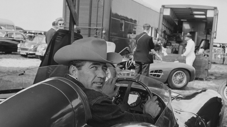 Carroll Shelby wearing a cowboy hat while behind the wheel of a racecar black and white