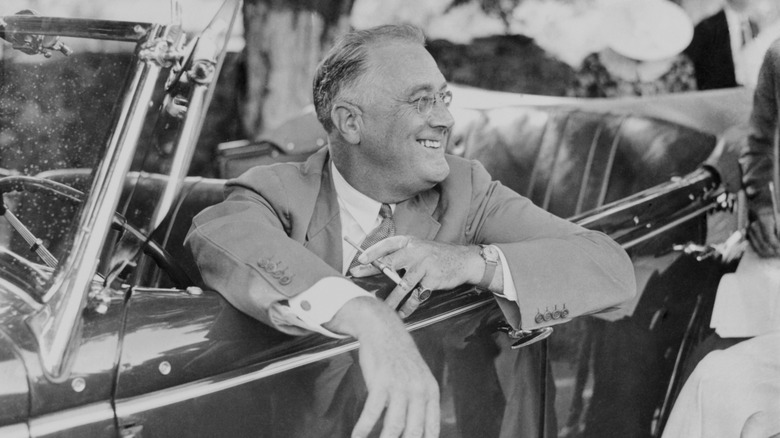 FDR hanging out of a car in a black and white photo