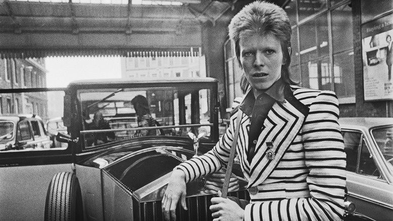 David Bowie leaning against a car