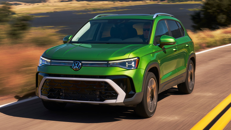 2025 Volkswagen Taos driving down a road with dual lane markings in the middle