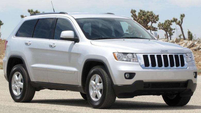 A white 2011 Jeep Grand Cherokee parked in front of a desert landscape