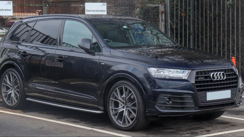 A black 2017 Audi Q7 in a parking space in front of a fence