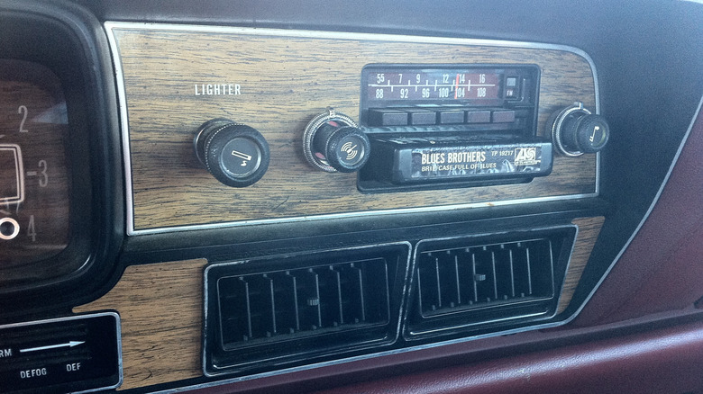 A crop of a 1978 AMC Matador center dash complete with 8-track player, dials and buttons for the radio, and a cigarette lighter.