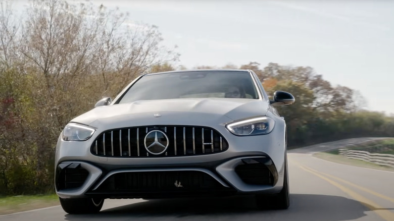 a 2024 mercedes amg c63 driving down a road on a fall day