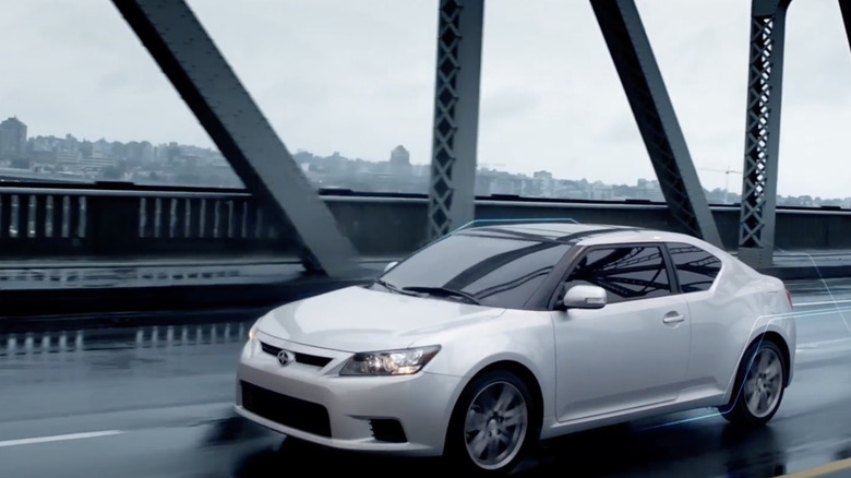 A silver Scion tC driving down a rainy bridge