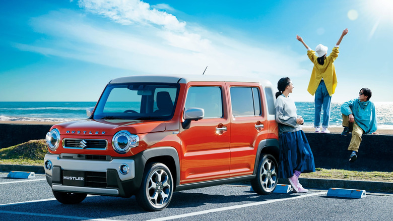 A Suzuki Hustler with three people hanging out at the back