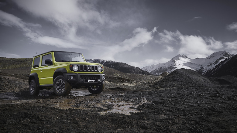 A green Suzuki Jimny in a muddy environment