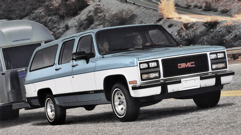 Blue and white GMC Suburban towing a trailer