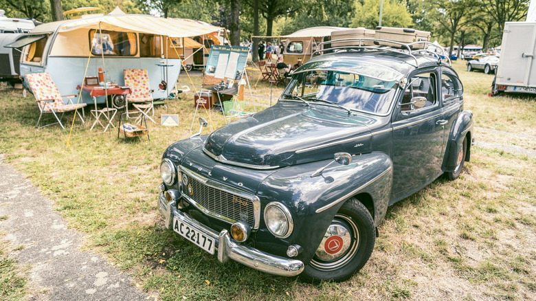 A green Volvo PV544 at a campsite