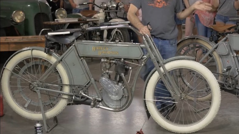A tour-guide stands beside the 1909 Harley-Davidson Model 5 in a museum
