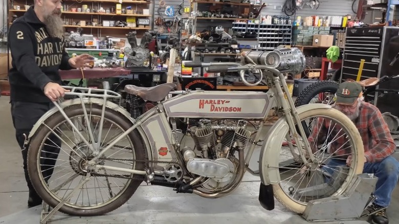 A 1912 Harley-Davidson in a workshop with two mechanics
