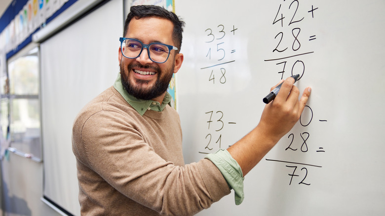 A man does some simple math on a whiteboard.