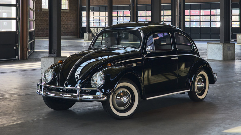Front 3/4 view of a black classic Volkswagen Beetle in a warehouse