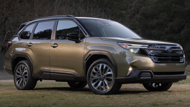 2025 Subaru Forester Hybrid parked in field with hill and trees in background