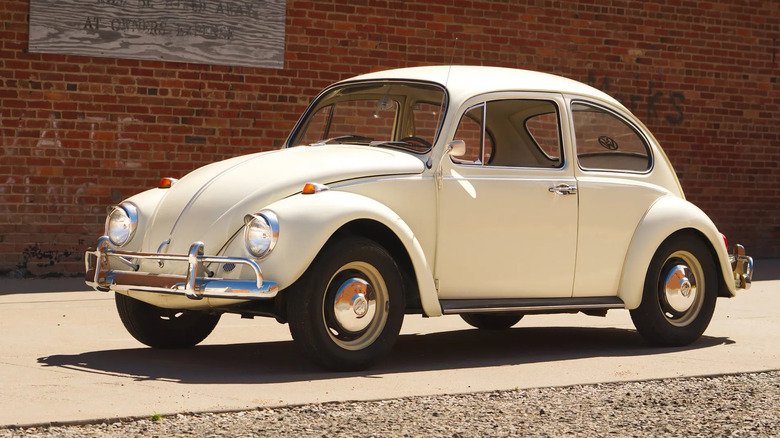 a white Beetle parked in front of a brick wall