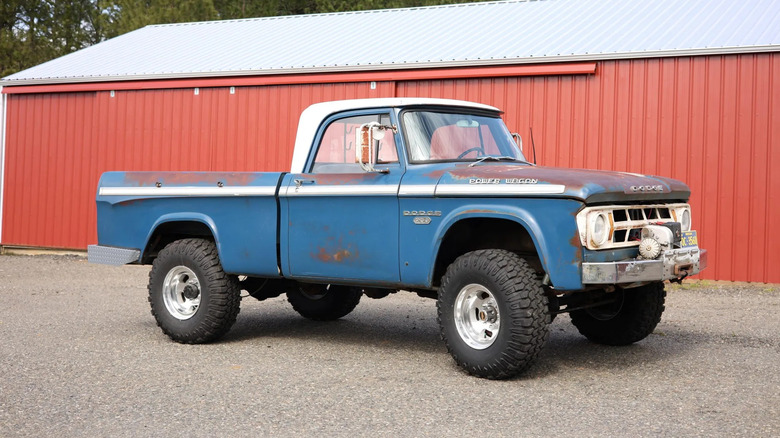A blue single cab Dodge Power Wagon parked in front of a red building