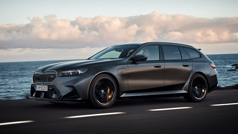 Front 3/4 view of a matte black BMW M5 Touring