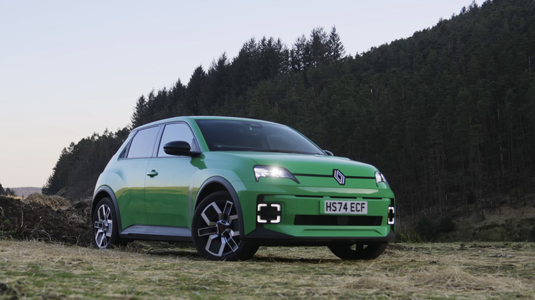 A green renault 5 parked near a forest at sunset