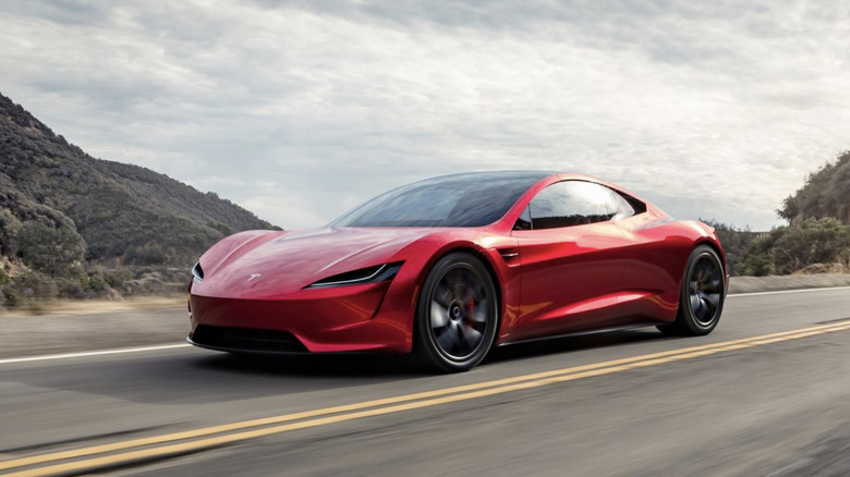 A red tesla roadster concept driving along a mountain road on a cloudy day