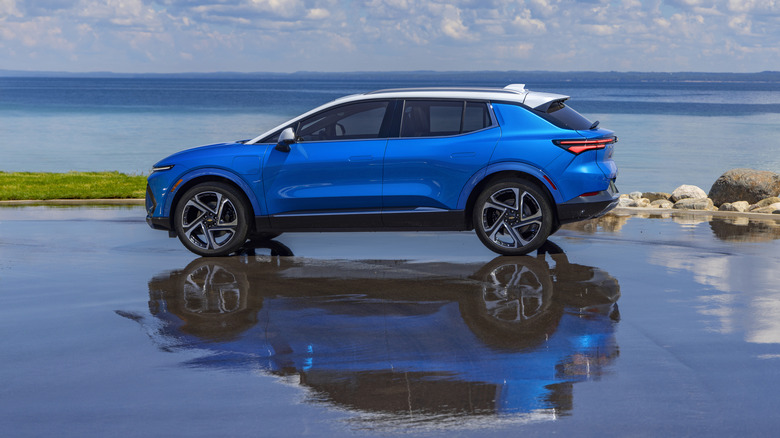 A blue pre-production 2025 Chevrolet Equinox 3LT with a white roof parked near a lake