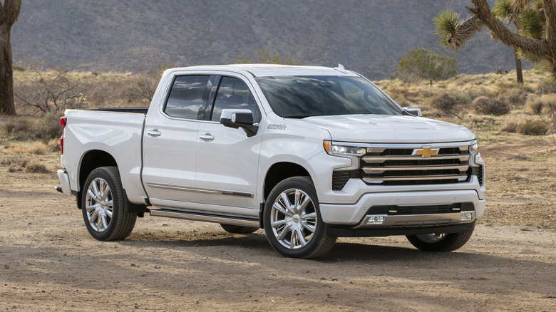 A front 3/4 view of a white 2022 Chevrolet Silverado High Country parked on dirt