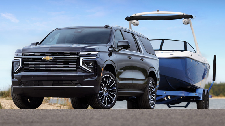A black 2026 Chevrolet Suburban High Country towing a boat
