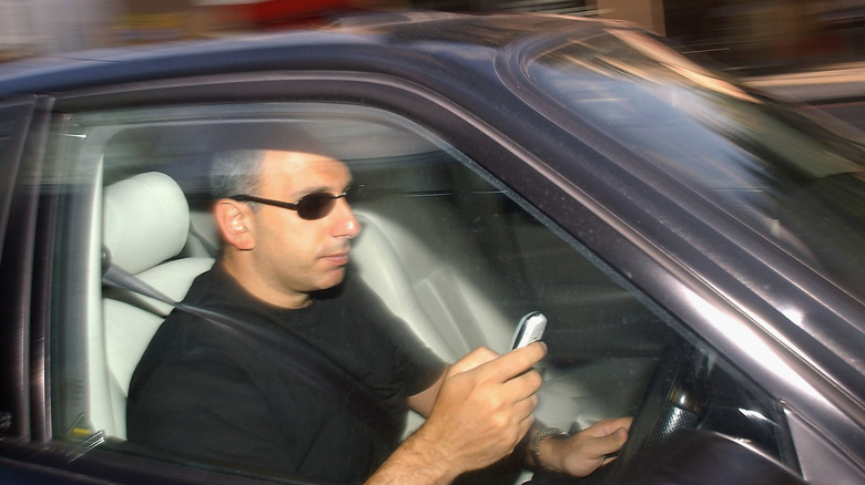 LONDON - JUNE 24: A man writes a text message on his mobile phone whilst driving in traffic on June 24, 2003 in London, England. The government has announced plans for a ban on talking on hand-held mobile phones while driving; this will go into effect by the end of the year.