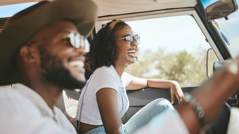 Travel, road trip and black people couple driving by countryside for holiday, journey and freedom with happiness. Trendy sunglasses, fashion and gen z friends in a car drive for vacation lifestyle