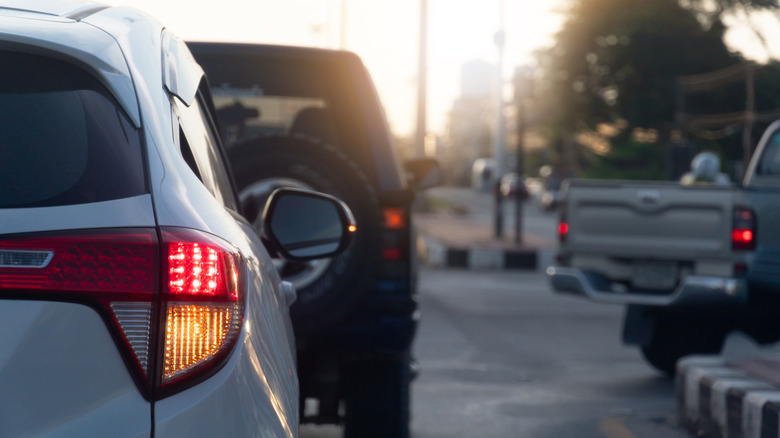 Rear side of cars on the road. Stop and open light brake with turn signal light. for U-turn on the asphalt road. Environment of morning time with sunrise.