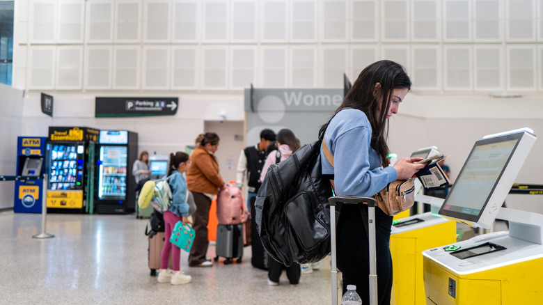 A woman using a kiosk to print a plane ticket