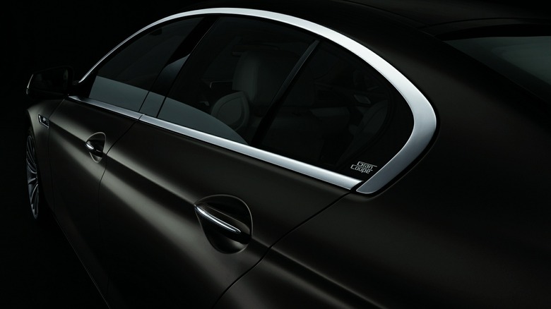 A close-up of the greenhouse of a black 640i Gran Coupe showing its Hofmeister kink in a black studio