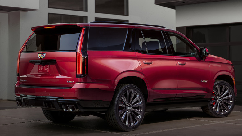 Rear ¾ view of the 2025 Cadillac Escalade-V, with a house in the background.