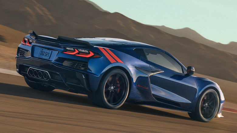 rear three-quarters shot of a blue C8 Corvette Gran Sport driving on a track in the desert in front of mountains and a blue sky