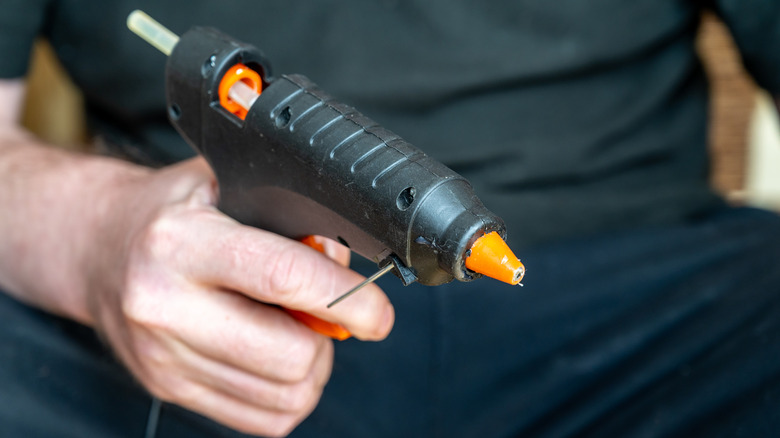 Man's hand holding a hot glue gun.