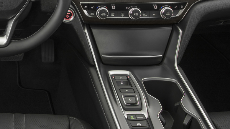 A close-up of the center console of the previous generation Accord with a black interior and its weird button shifter