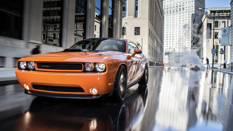 An orange Challenger R/T Shaker parked on a wet street in Detroit with the reflection bouncing off the pavement