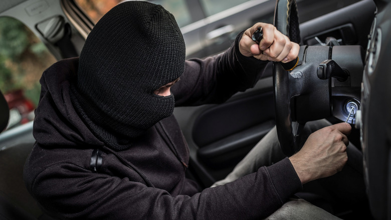 Close up shot of a thief using a screwdriver to start a vehicle